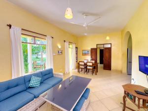 a living room with a blue couch and a table at Flametree Beach Homes in Diani Beach