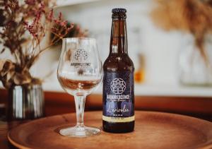 a bottle of beer next to a glass on a table at Hôtel La Tour des Anglais in Mayenne +39 photos