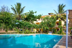 a large blue swimming pool in front of a building at Flametree Beach Homes in Diani Beach