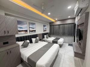 a bedroom with two beds and a television in it at Hotel Palash Icon in Ahmedabad