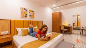 a woman sitting on a bed with a book at Zostel Noida in Noida