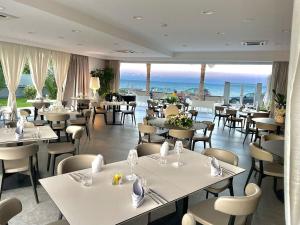a restaurant with tables and chairs and the ocean at Santantonioresort in Riposto