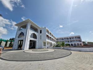 a large white building with a clock in the middle at Three Oceans Resort in Kanyakumari