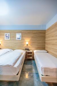 two beds in a room with wooden walls at Ferrucci Rooms in Marina di Cecina