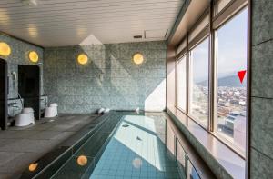 a swimming pool in a building with a view at Saijo Urban Hotel in Saijo