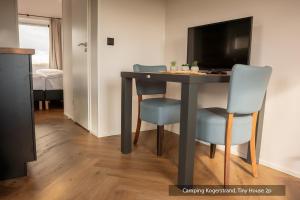a dining room table with two chairs and a television at Texelcampings - Kogerstrand in De Koog