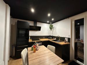 a kitchen with a wooden table with chairs and a sink at Premium suite with jacuzzi 4 étoiles in Pleyber-Christ +43 photos