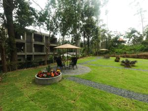 a garden with a table and chairs and an umbrella at Ayana Gardens Ella in Ella +53 photos