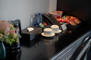 a black counter top with two cups and a vase of flowers at C'Lau Hotel Ninh Binh - A Gem Nestled in Ancient Quarter in Ninh Binh