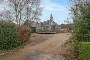 a large wooden house with glass windows on a driveway at The Orchard Annexe, Framlingham in Framlingham