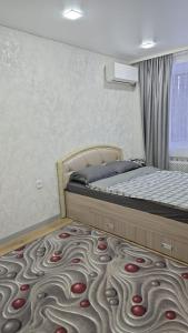 a bedroom with a bed with a carpet with red cherries at Возле Нарыка in Ekibastuz