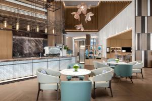 a restaurant with tables and chairs and a kitchen at Deqing Marriott Hotel in Huzhou