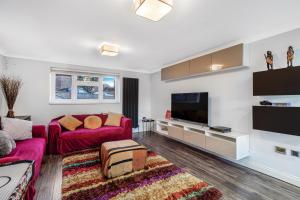 a living room with two red couches and a flat screen tv at 4 BR 6 Beds 3 Bath PS4, Pool Table Parking x4 Close to Legoland & Windsor in Maidenhead