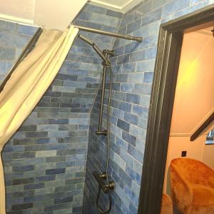 a shower in a bathroom with a blue tile wall at B en B de 8 Wieken in Oosterwolde