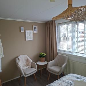 a bedroom with two chairs and a table and a window at B en B de 8 Wieken in Oosterwolde