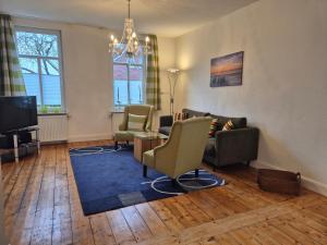 a living room with a couch and chairs and a tv at Stadtvilla Norden in Norden