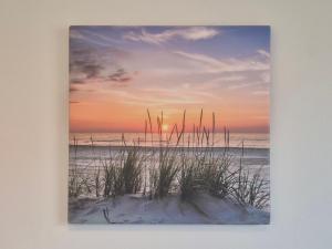 a picture of a beach at sunset with grass at Zauberhaus in Norddeich