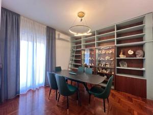 a dining room with a table and green chairs at Appartamento Rosa in Gualdo Tadino