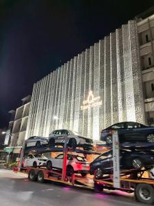 a large building with cars on a trailer in front of it at S2S Queen Trang Hotel in Trang +82 photos