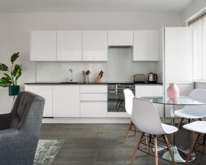 a kitchen with white cabinets and a table and chairs at Abbott House by Viridian Apartments in St. Albans