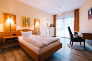 a bedroom with a bed and a desk and a chair at hotel zentlinde in Mossautal +34 photos