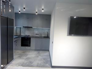 a kitchen with blue cabinets and a flat screen tv at Balka-centr Tiraspol in Tiraspol