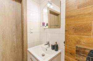 a white bathroom with a sink and a mirror at Perła Bałtyku - kawalerka z dostępem do Resort &MediSpa in Sianozety