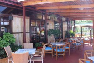 a restaurant with tables and chairs and windows at Asterias Bay Hotel By Anayia All Inclusive Resorts in Theologos