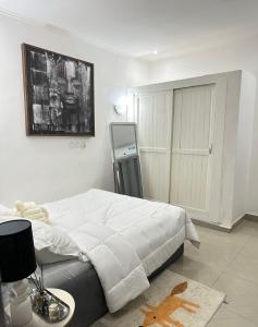 a bedroom with a white bed and a painting on the wall at Bungo Home - Suite Chambre & salon à 2 min de la plage in Pointe-Noire