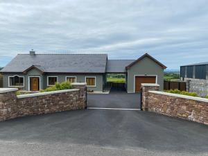 a house with a stone fence and a driveway at Studio Sleeps 2 -Private Hot Tub -Enclosed Garden in Killarney