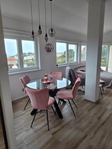 a dining room with a glass table and pink chairs at Apartment Mia 2 in Rab