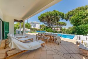 an outdoor patio with a table and chairs and a pool at Villa Mia - Vale do Lobo in Vale do Lobo