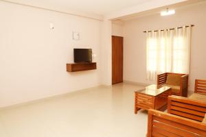 a living room with a tv and a couch and a table at Fine Homes in Kalpetta