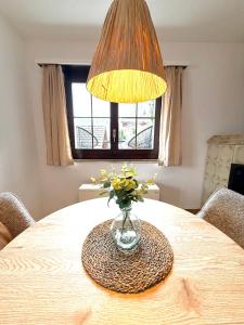 a vase of flowers on a table with a lamp at Studio Lake View Faulensee in Faulensee