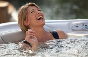 a woman is laughing in a bath tub at Gites en ardennes & wellness - Ovifat - Coquelicots & Orchidees in Ovifat