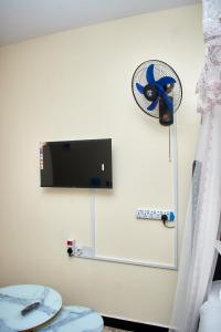 a room with a toilet and a tv on the wall at Deluxe Homes 2, Voi in Voi