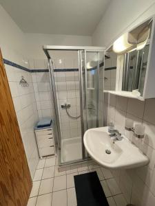 a white bathroom with a shower and a sink at Smans Fewo in Neustadt in Holstein +2 photos