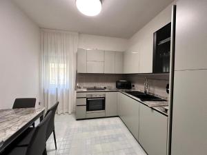 a kitchen with white cabinets and a table and a counter at Appartamento Rosa in Gualdo Tadino