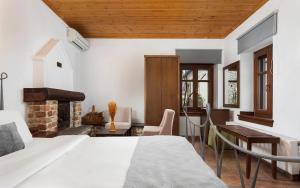a bedroom with a bed and a desk and a fireplace at Archontiko Papoutsi Pelion in Mouresi