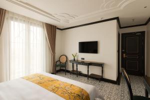 a bedroom with a bed and a desk and a television at C'Lau Hotel Ninh Binh - A Gem Nestled in Ancient Quarter in Ninh Binh