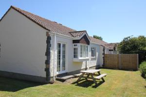 un piccolo cottage bianco con un tavolo da picnic nel cortile di Briquet Cottages, Guernsey,Channel Islands a St Saviour Guernsey