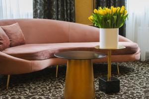 a pink couch with a vase of yellow flowers on a table at Hotel Jelgava in Jelgava