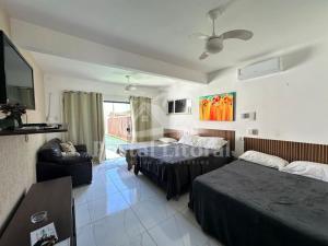 a hotel room with two beds and a television at Bangalô MAR & SOL in Saquarema