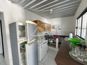 a kitchen with a refrigerator and a counter top at Bangalô MAR & SOL in Saquarema