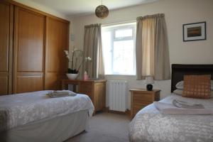 セイント・セイヴャー・ガーンジーにあるBriquet Cottages, Guernsey,Channel Islandsのベッドルーム1室(ベッド2台、窓付)