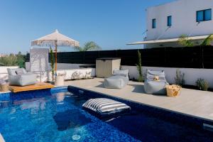 a swimming pool with chairs and an umbrella on a patio at Nesea Seaside Luxury Escape in Protaras
