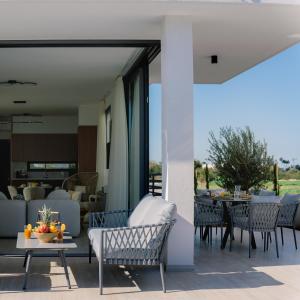 a patio with chairs and tables and a living room at Nesea Seaside Luxury Escape in Protaras