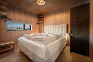 a bedroom with a large white bed with wooden walls at Secluded Lodge - Stunning Views! in Storøya