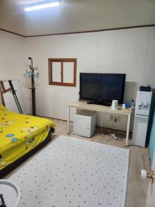 a living room with a tv and a table with a bed at Chenal Motel in Daegu