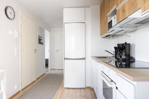 a kitchen with white cabinets and a refrigerator at Spot Apartments Oulu in Oulu